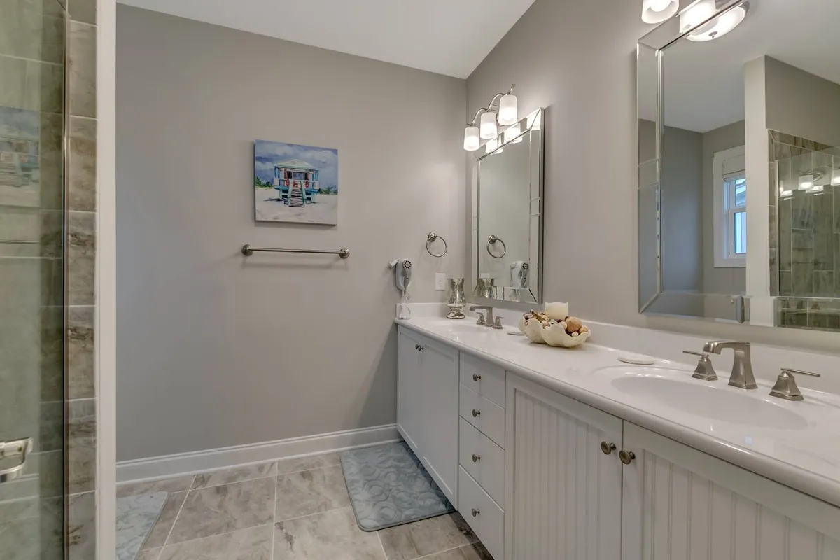 A serene bathroom featuring a double vanity with large mirrors and tasteful wall art. The tranquil mood and ample amenities suggest a space designed for pampering and convenience.